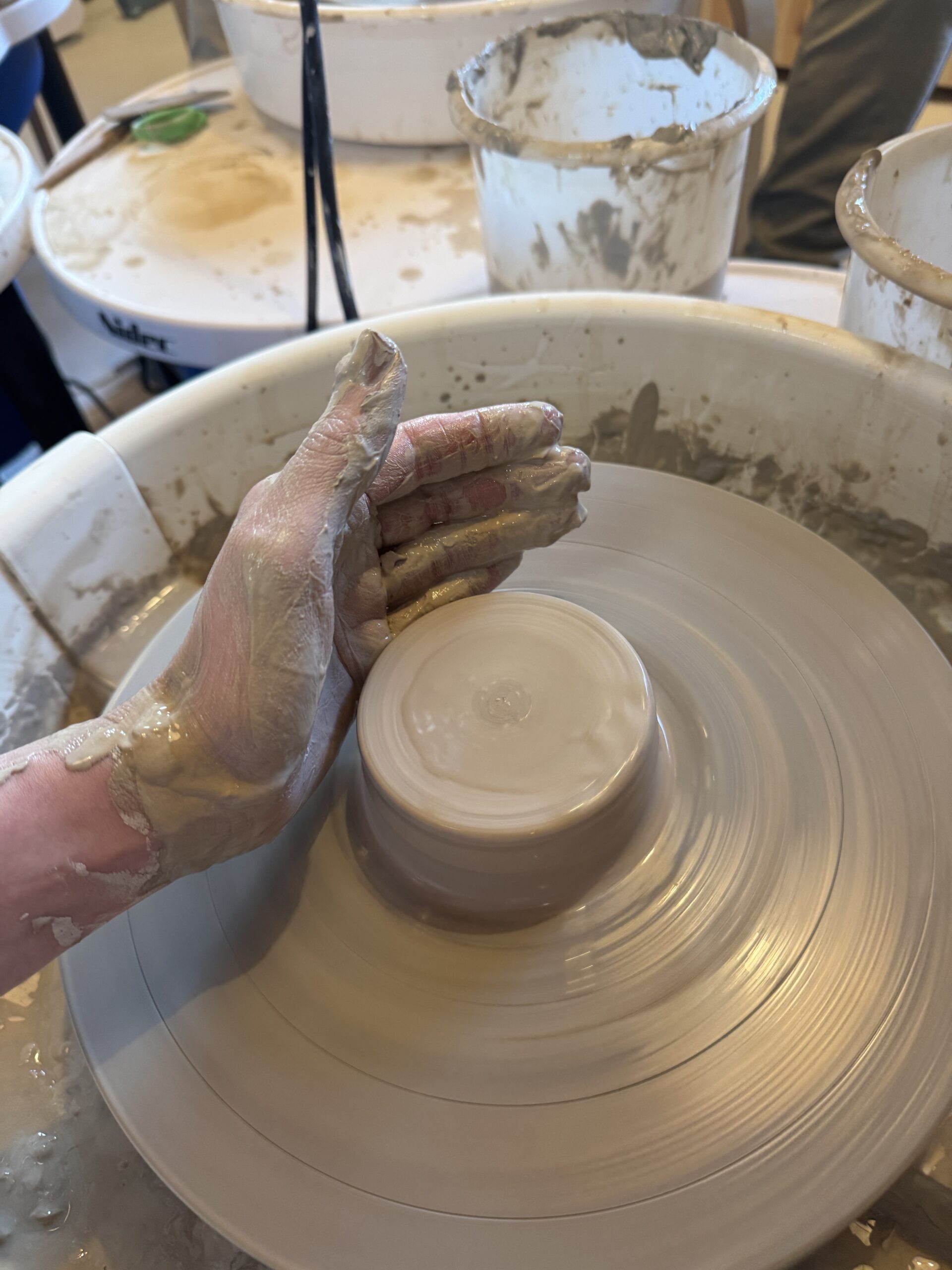 Hand working on the potterywheel with clay. Making a pot or mug.
