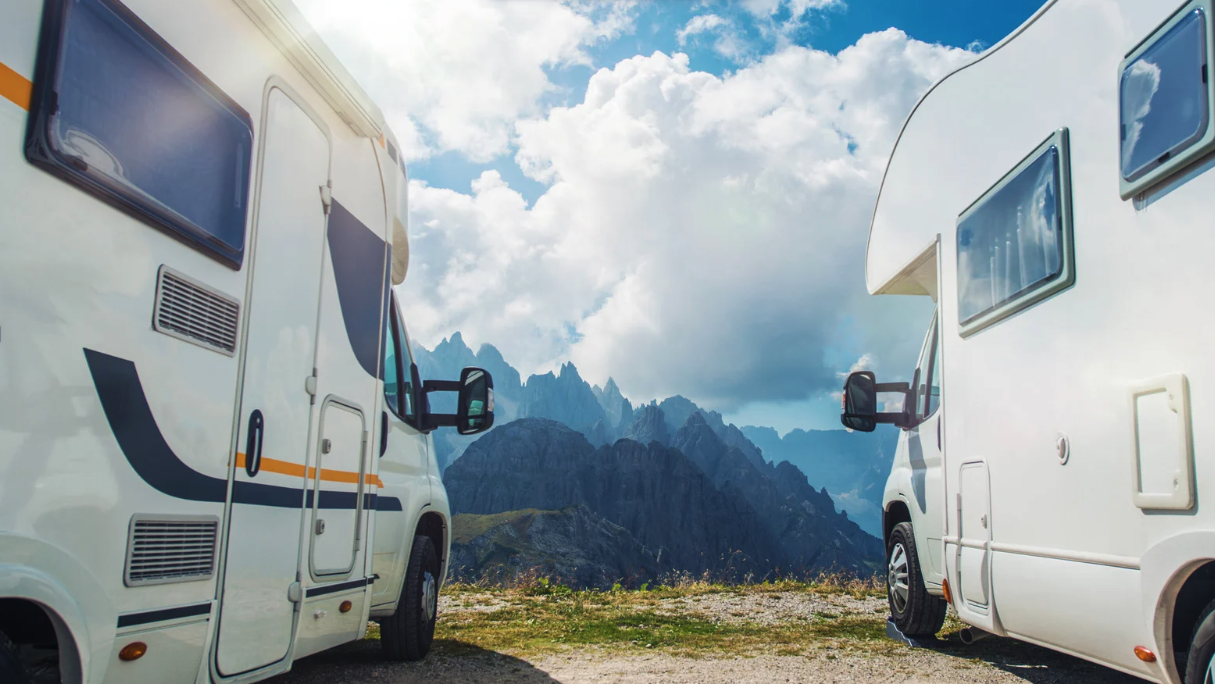 Two campers are standing with a beautiful mountain view